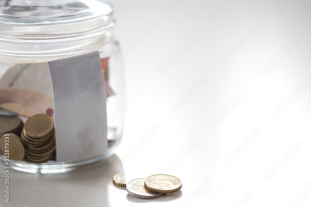 Jar of glass with metal coins and paprer money on white table save for future Jar of glass with metal coins and paprer money on white table save for future