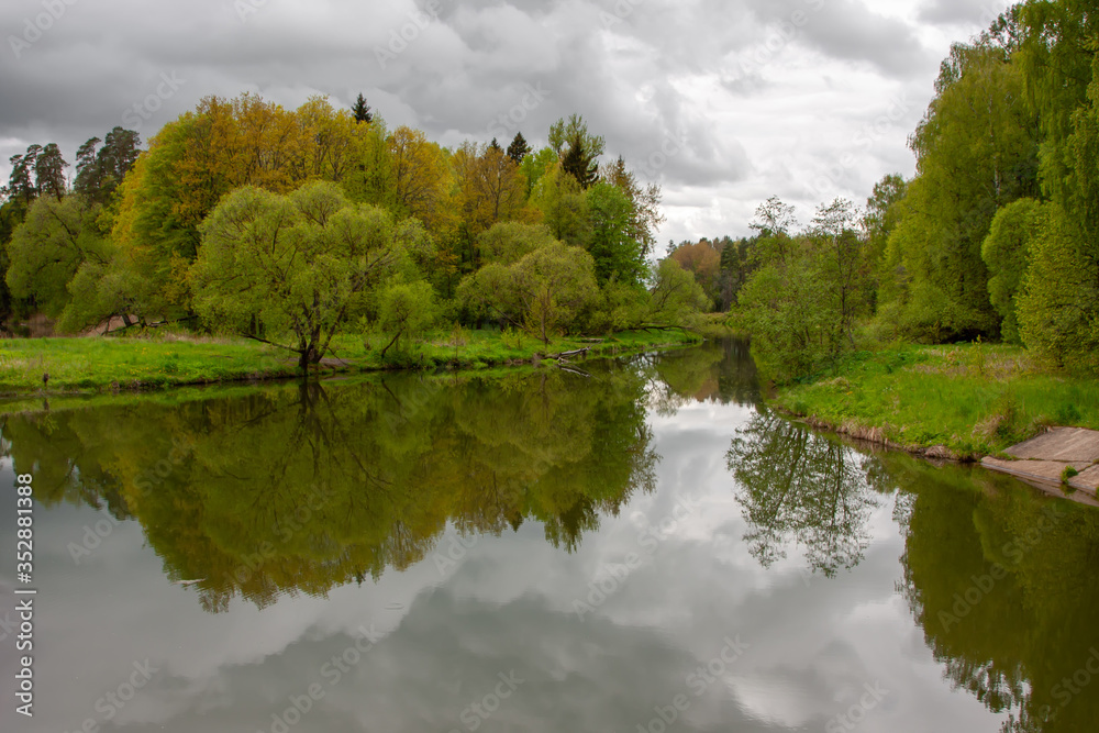 Beautiful spring forest in the reflection of a beautiful river under a cloudy sky Beautiful spring forest in the reflection of a beautiful river under a cloudy sky
