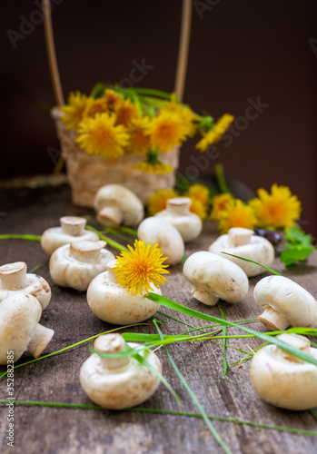 Champignons in a basket and yellow dandelions on a wooden rustic table