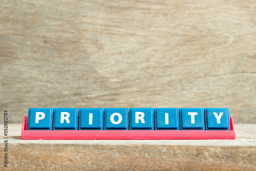 Fototapeta premium Tile letter on red rack in word priority on wood background