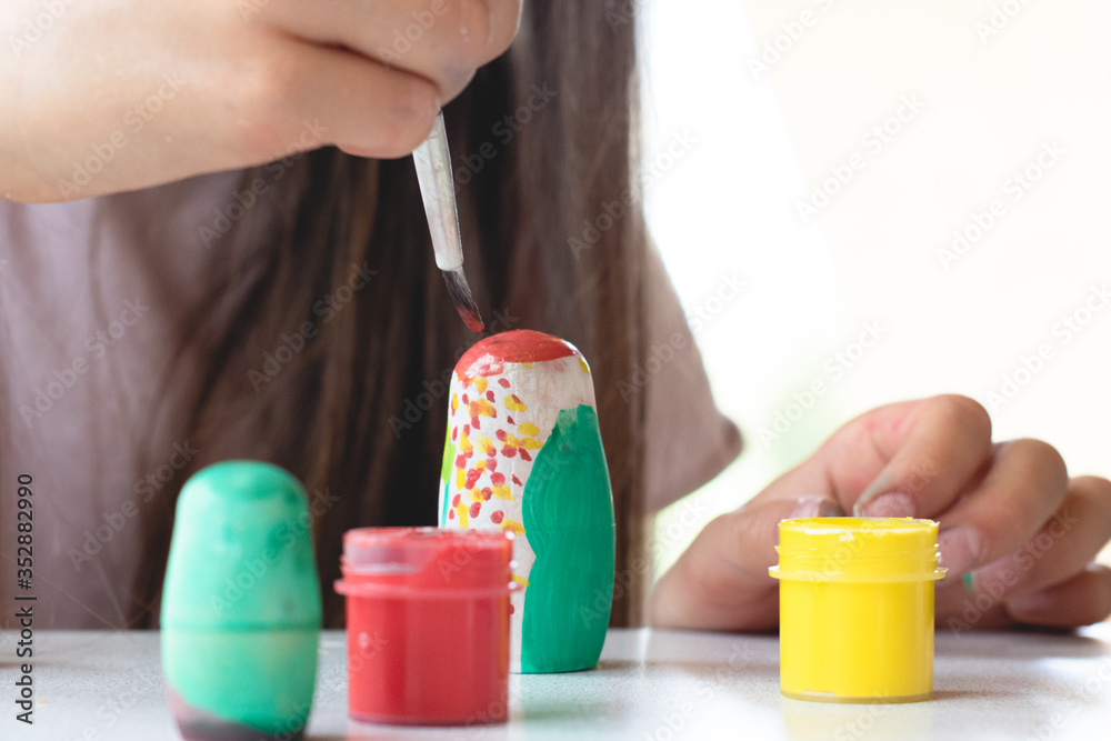 A child paints a wooden blank of a nesting doll. Children's crafts A child paints a wooden blank of a nesting doll. Children's crafts