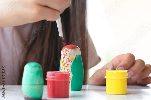 A child paints a wooden blank of a nesting doll. Children's crafts
