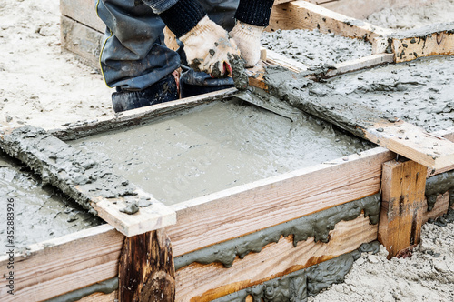 A construction worker levels the wet cement after pouring for the Foundation of the house.