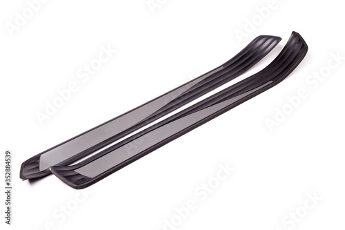 A pair of black plastic decorative door sills in an automobile parsing for sale or repair in a workshop on a white isolated background in a photo studio. photo