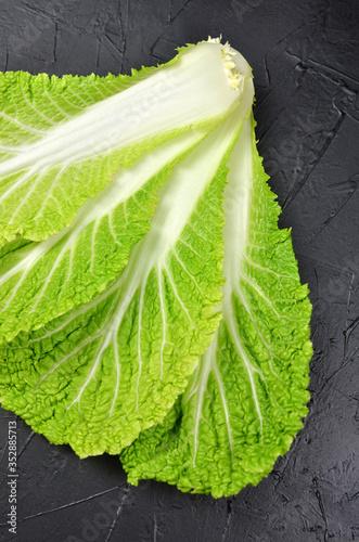 Green chinese cabbage leaves on black background. Vegan food concept. photo