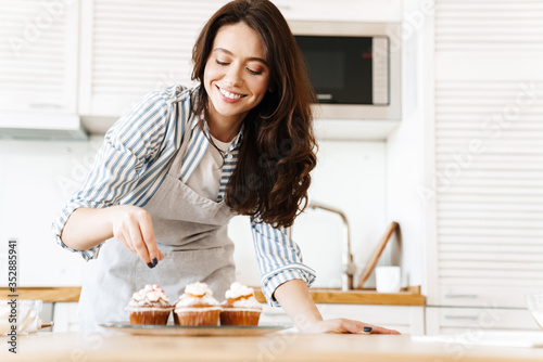 Image of caucasian happy woman smiling and cooking muffins
