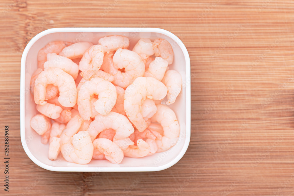 Boiled shrimps in white bowl on wooden kitchen board, top view Boiled shrimps in white bowl on wooden kitchen board, top view