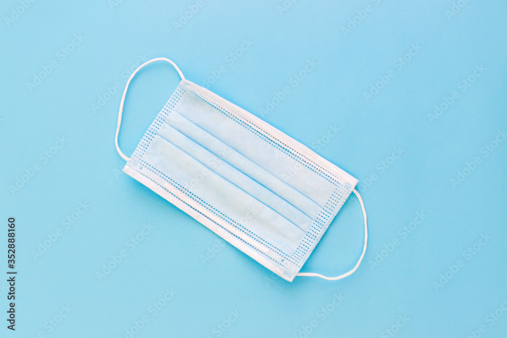 White medical face mask on a bright blue background White medical face mask on a bright blue background