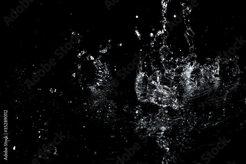 Splashes and drops of water are on a black background. © schankz