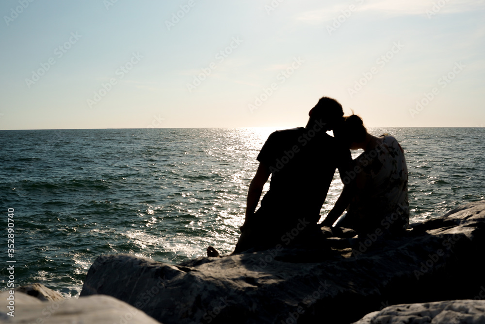 Silhouette of young couple watching the sunset at the sea
