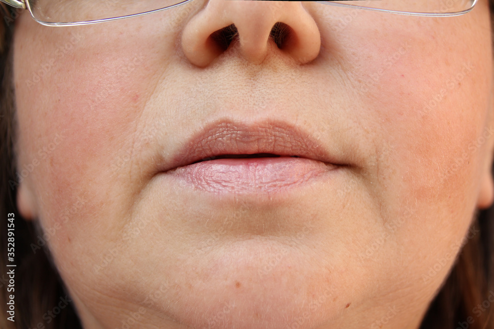 Fototapeta premium lips, mouth and chin of a middle-aged woman, part of the face close-up, fine wrinkles on the face, spots, the concept of cosmetic anti-aging procedures, facial massage