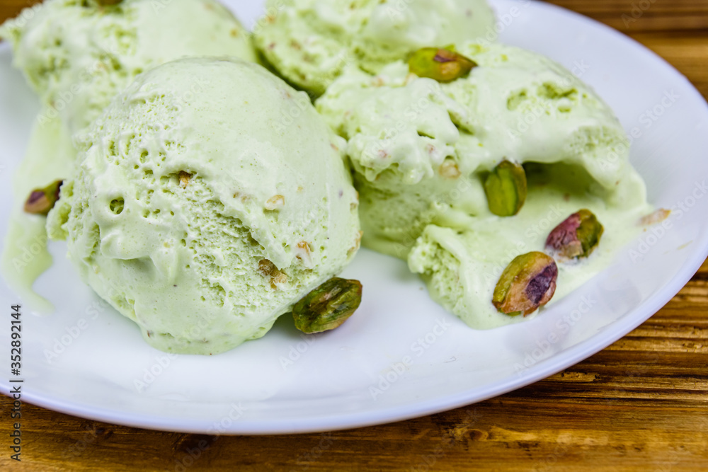 Glass bowl with pistachio ice cream balls and nuts on a wooden table Glass bowl with pistachio ice cream balls and nuts on a wooden table