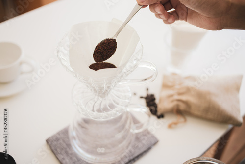 Close up. roasted coffee on a stainless spoon, with professional of barista pour Roasted coffee for dripping hot coffee into the cup with equipment, tool brewing at kitchen home photo