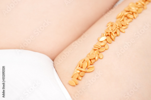 Wax beans on woman's leg in row. Concept of depilation and epilation.