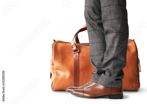 Man is standing with a large brown leather bag