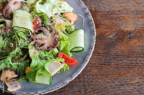 Healthy delicious sea food salad with octopus mussels squid etc top view on wooden table with copy space