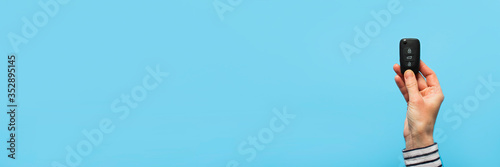 Wallpaper Mural Female hand holds car keys on a blue background. Concept car, car rental, gift, driving lessons, driving license. Banner. Flat lay, top view Torontodigital.ca