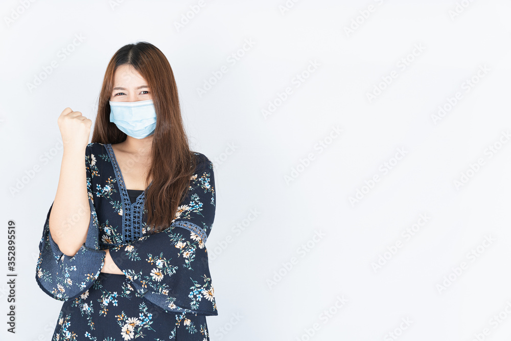 Asian beautiful happy hipster woman wearing a medical protection face mask for protect the coronavirus, filter dust PM 2.5 and cold and raise her hand to fight them on white background Asian beautiful happy hipster woman wearing a medical protection face mask for protect the coronavirus, filter dust PM 2.5 and cold and raise her hand to fight them on white background