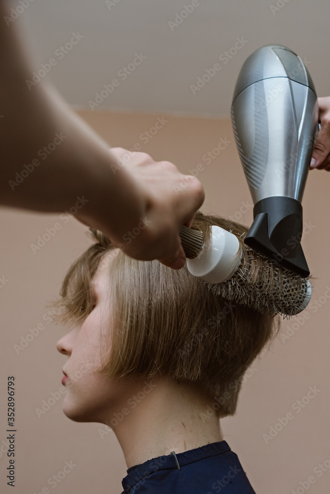 Fototapeta premium Young blonde girl doing hairdryer styling at home