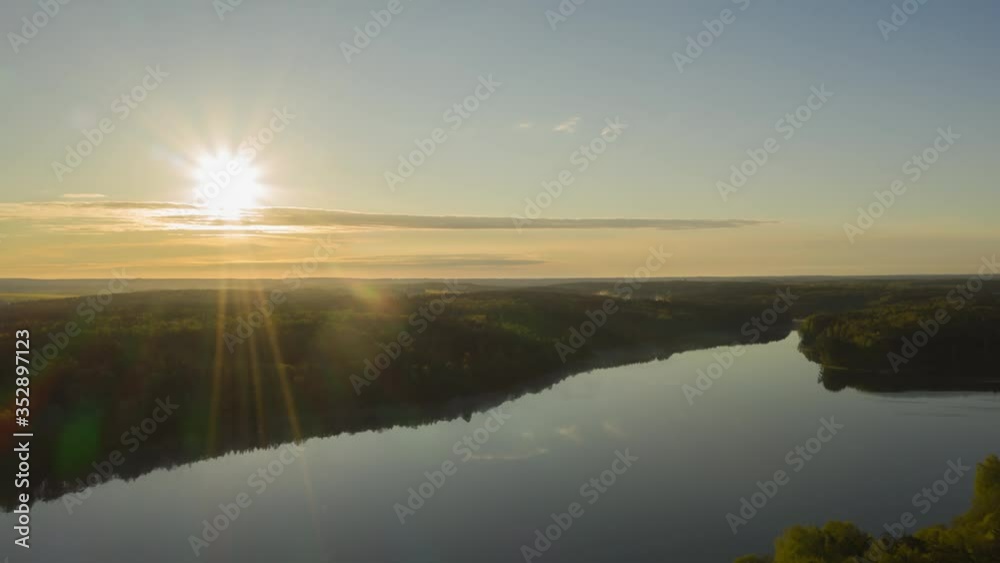 Hyperlapse drone flying over lake at sunrise. Time-lapse clouds of fog above water surface. Early morning haze. Haze over river countryside. Pine trees forest on horizon reflected in water