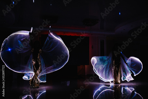 Dancers in suits with LED lamp, light show in movement, LED show in the night club party. Laser show performance, dancing with the sparks.