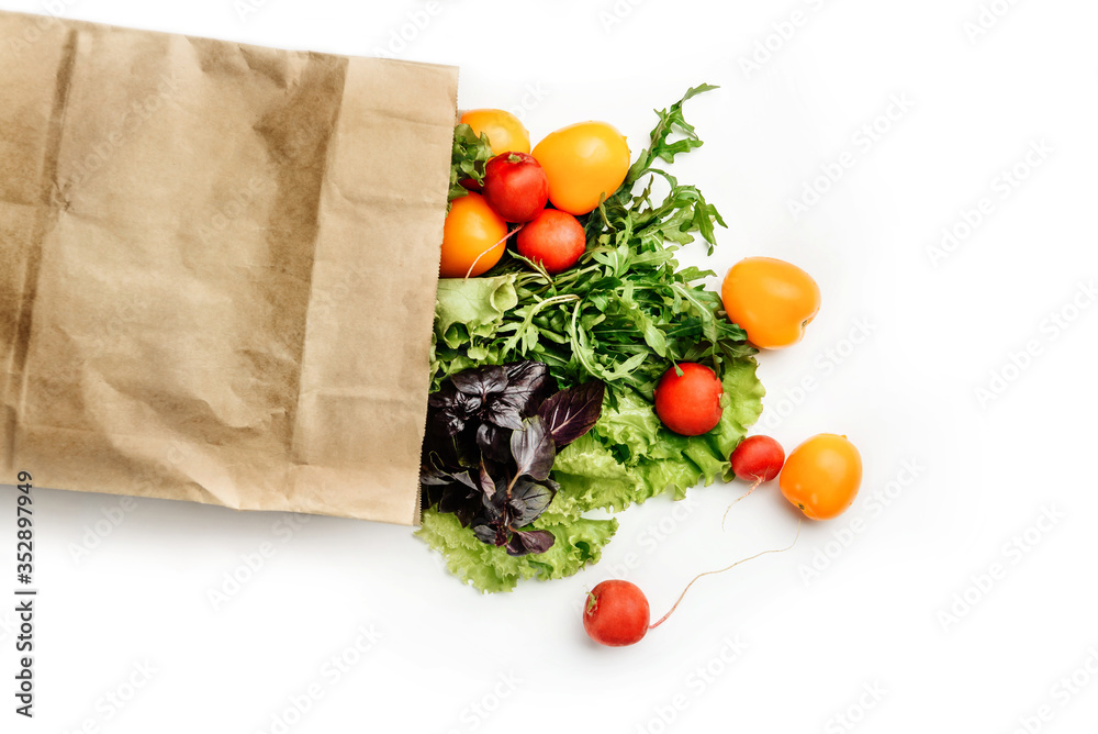Paper bag with lettuce, basil, arugula, radish and tomatoes isolated on a white background. Paper bag with lettuce, basil, arugula, radish and tomatoes isolated on a white background.