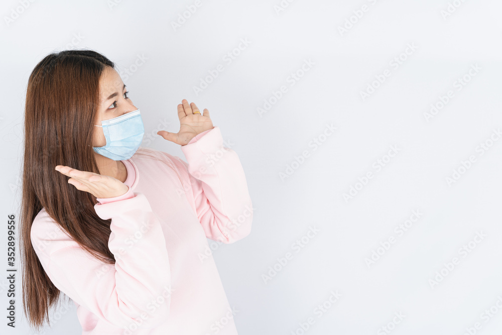 Asian beautiful happy hipster woman wearing a medical protection face mask for protect the coronavirus, filter dust PM 2.5 and cold and raise her hand to cheer up on white background Asian beautiful happy hipster woman wearing a medical protection face mask for protect the coronavirus, filter dust PM 2.5 and cold and raise her hand to cheer up on white background