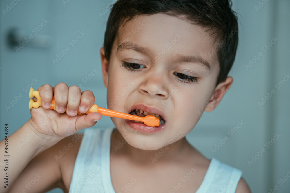 cute, concentrated kid brushing teeth in bathroom cute, concentrated kid brushing teeth in bathroom