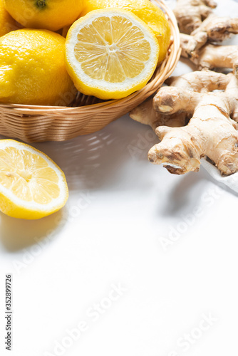 close up view of basket of fresh lemons and ginger root on napkin on white background