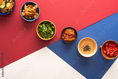 Φωτογραφία top view of bowls with korean side dishes and oil on blue, crimson and white