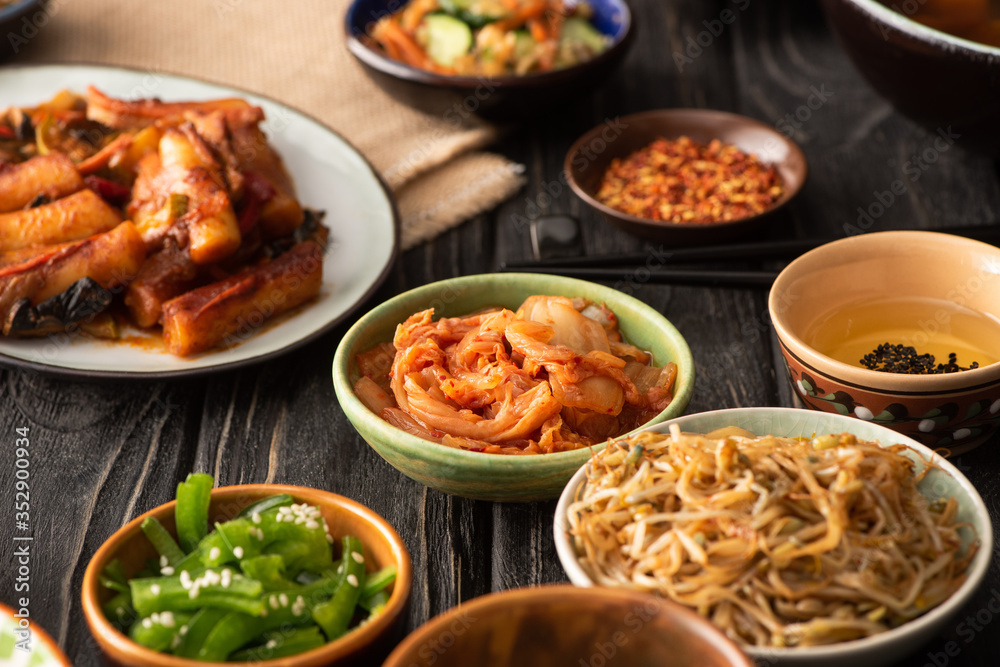 selective focus of spicy kimchi near topokki and korean side dishes