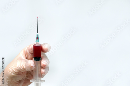 hand doctor in a glove holds a syringe with blood, a vaccine