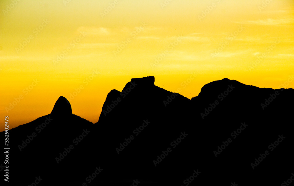 silhouette of the mountain of Rio de Janeiro Two Hill Brothers, Gavea stone and Beautiful Stone in a beautiful sunset.