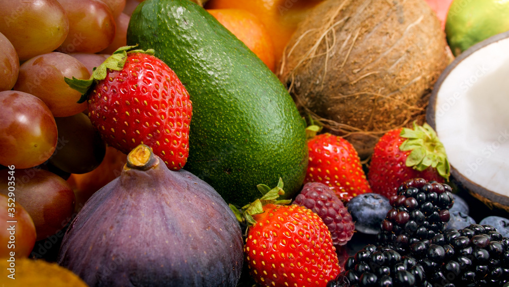 Closeup photo of tropical and exotic fruits. Berries, cocnuts, grapes, figs and avocado.