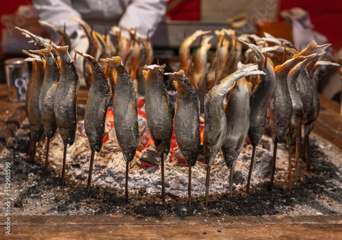 Japanese ayu fish skewers also called sweetfish grilled with salt and cooked in circle in a traditional robatayaki cooking around hot charcoals on a irori sunken hearth. photo