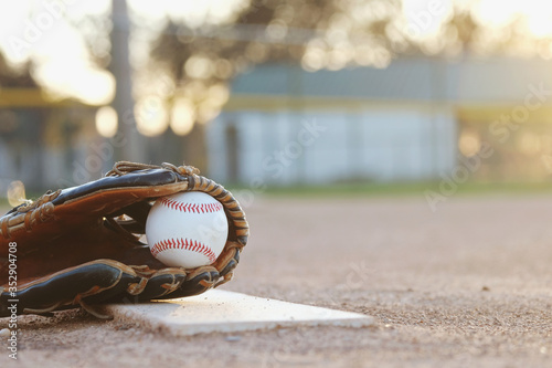 Photography Baseball in glove close up with blurred sports field in background at sunset with copy space