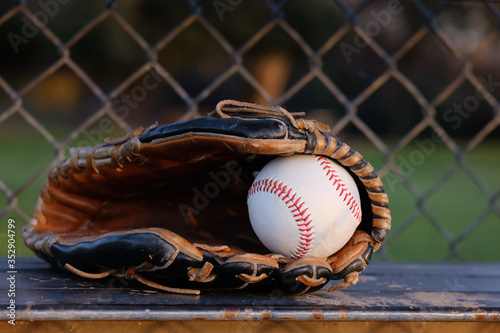 Fotografie Baseball glove with ball for game close up on dugout bench.