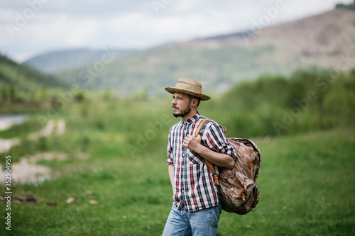 Young bearded man in a straw hat with a backpack