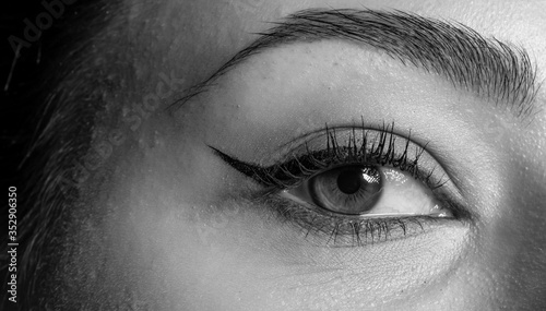 Close-up photo of woman eye with eyeliner makeup. Black and white.