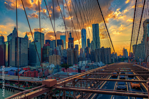 On the bridge facing Manhattan as cars drive by with people walking bayside we observe a wonderful sunset.