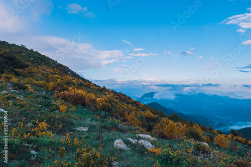 A picturesque wide landscape view of the French Alps mountains covered in clouds in the evening (Col de Rigaudon, Alpes-Maritimes, France)