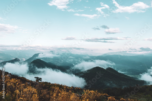 A picturesque wide landscape view of the French Alps mountains covered in clouds in the evening (Col de Rigaudon, Alpes-Maritimes, France)