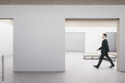 Businessman walking in exhibition interior with bench.