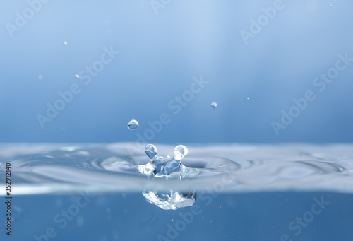 Water drops splash and circle reflextion background.Close up rain drops falling into the water and ripples of light blue.