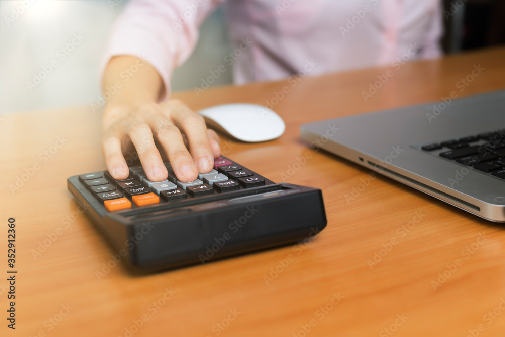 Women hand using calculator on office desk. Female hand press calculator. Business woman hand using calculator at office. Family budget calculation on wood table. Women hand using calculator on office desk. Female hand press calculator. Business woman hand using calculator at office. Family budget calculation on wood table.