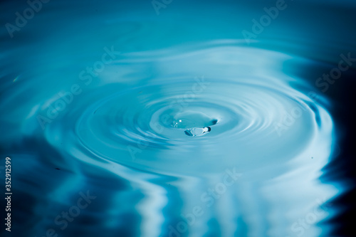 Water drops splash and circle reflextion background.Close up fresh water drops falling into the water and ripples of light blue.