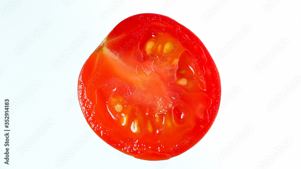 Closeup photo of juicy ripe tomato skice over white background. Abstract background of vegetables and fruits Closeup photo of juicy ripe tomato skice over white background. Abstract background of vegetables and fruits