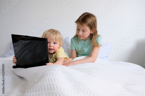 little girl and boy are watching cartoons on a laptop