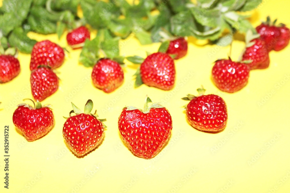 Strawberry berries with mint isolated on a yellow background. Strawberries and mint leaves on a bright yellow background. Background for the design of banners, websites, blogs. Copy space. Red berries