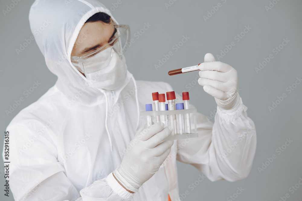 Corona virus theme. Man in a protective suit. Doctor looks at the blood tube. Corona virus theme. Man in a protective suit. Doctor looks at the blood tube.